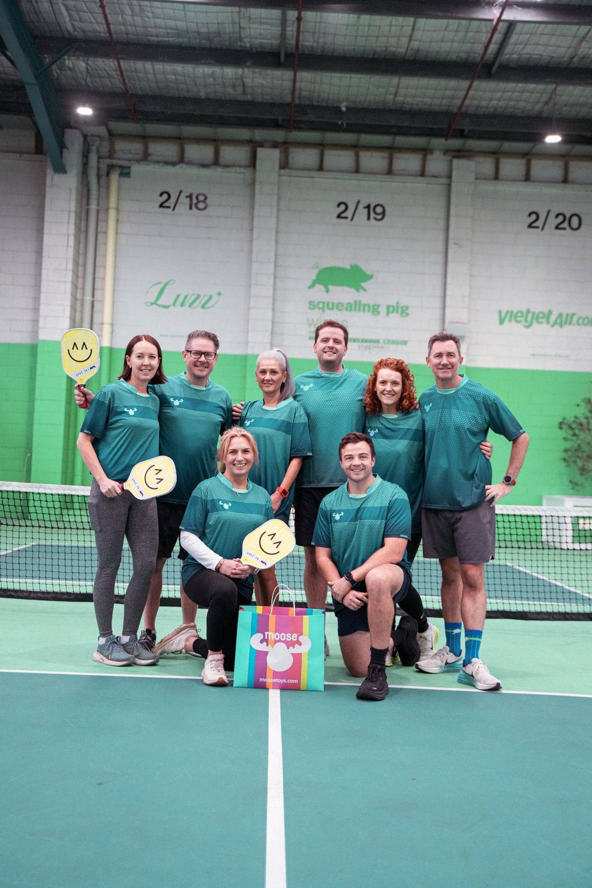A corporate team posing together on court