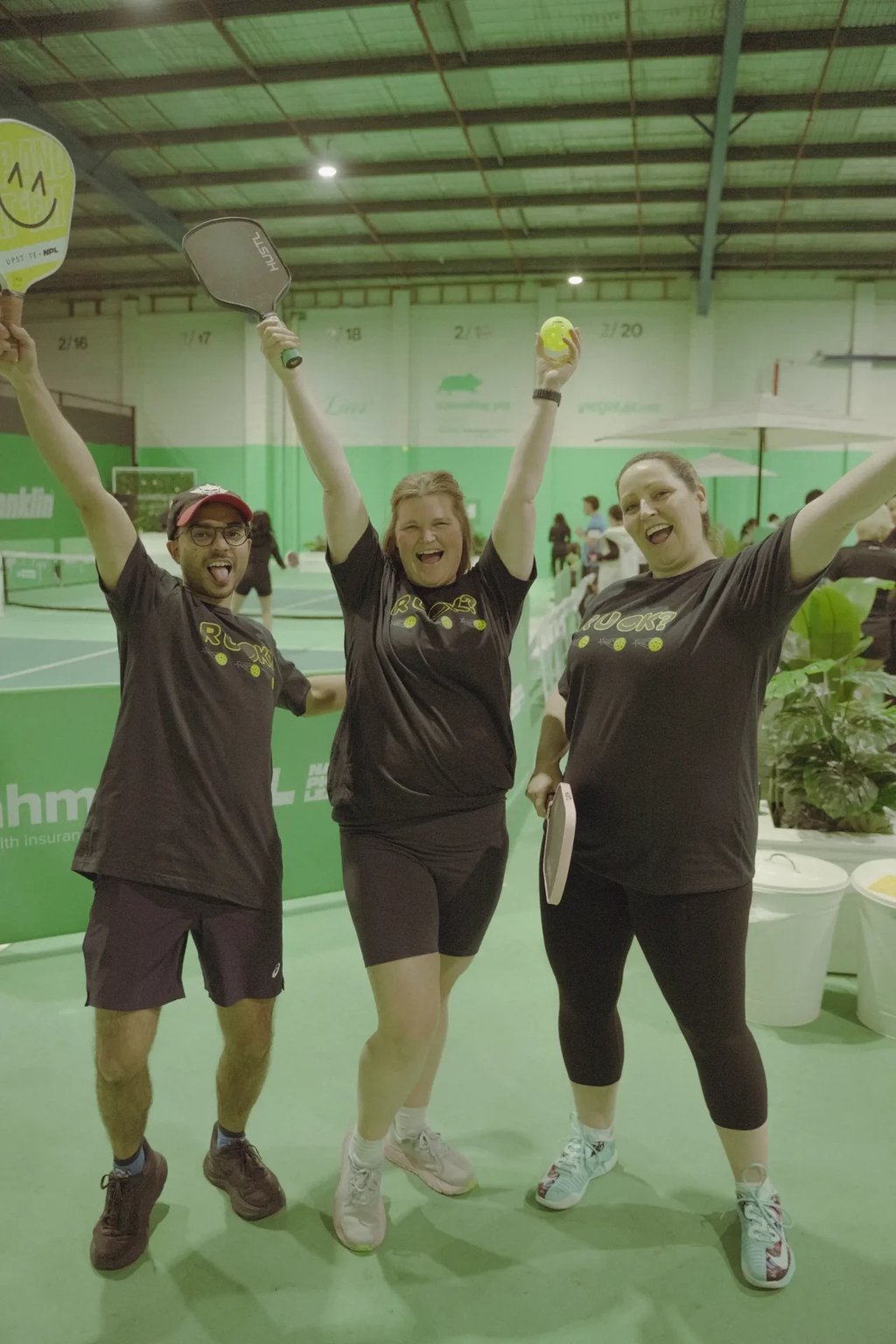 Three players celebrating together with paddles raised at The Jar South Melbourne